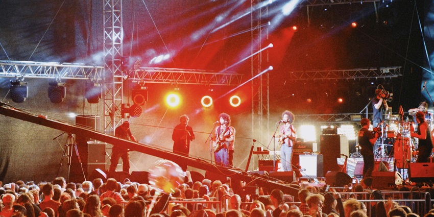 An image of Nocturne where performers perform on stage in front of a crowd during a party