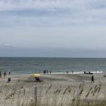 Sunny beach in Carolina Beach, North Carolina, with gentle waves and a clear blue sky.