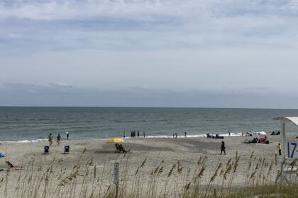 Sunny beach in Carolina Beach, North Carolina, with gentle waves and a clear blue sky.