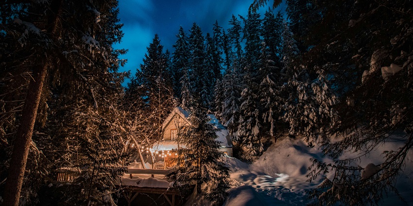 An image of the Northern Lights Resort with a cosy cabin beneath the glowing aurora borealis.