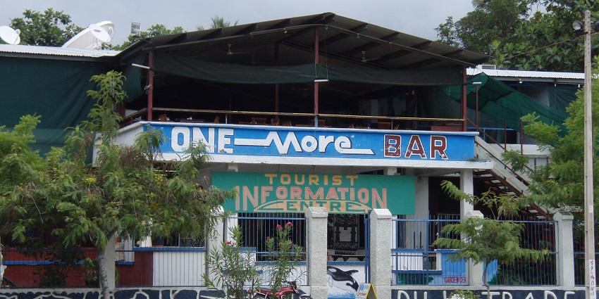 One more bar with a motorcycle in front of the entrance and signage on the wall.