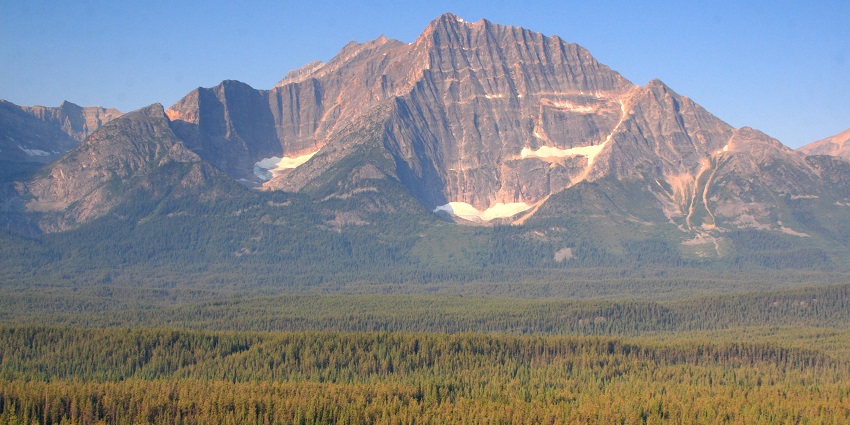 A majestic mountain range in Jasper National Park with snow-capped peaks and dense forest