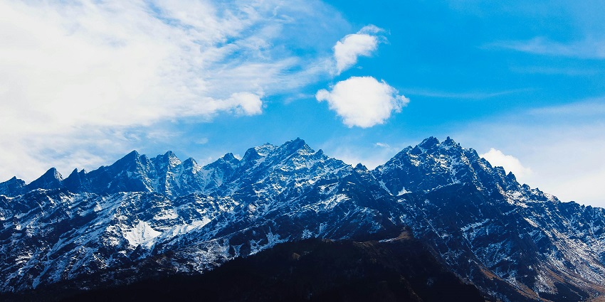 Image of picturesque mountains surrounded by lush greenery under clear blue sky
