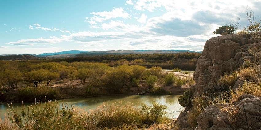 Sunny view of river in Texas and rock mountains surrounded by lush green trees
