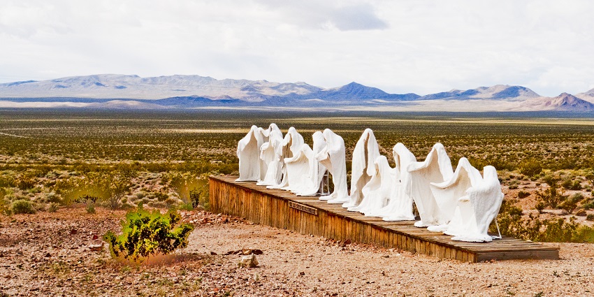 Abstract ghostly sculpture in Rhyolite, Nevada desert, with rugged mountains in the backdrop