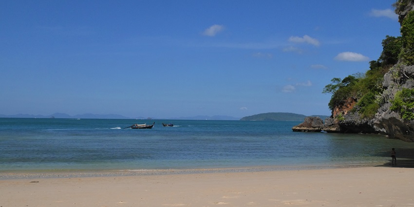 Image of serene each view with clear blue water and clear blue sky surrounded by rocks