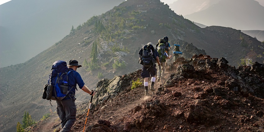 A view of trekkers resting in a background covered by the most scenic lush green hills