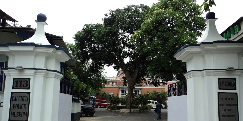 A view of Police Museum gate from outside surrounded by trees during day time