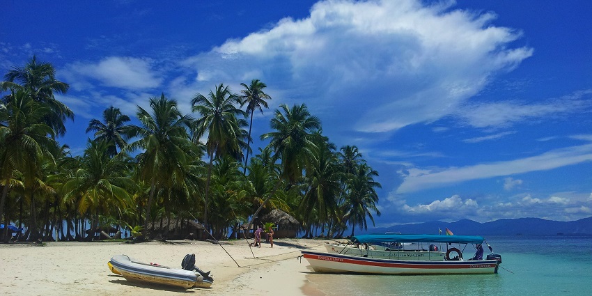 Panoramic view of rich hills, boats on the beach, and clear blue skies.