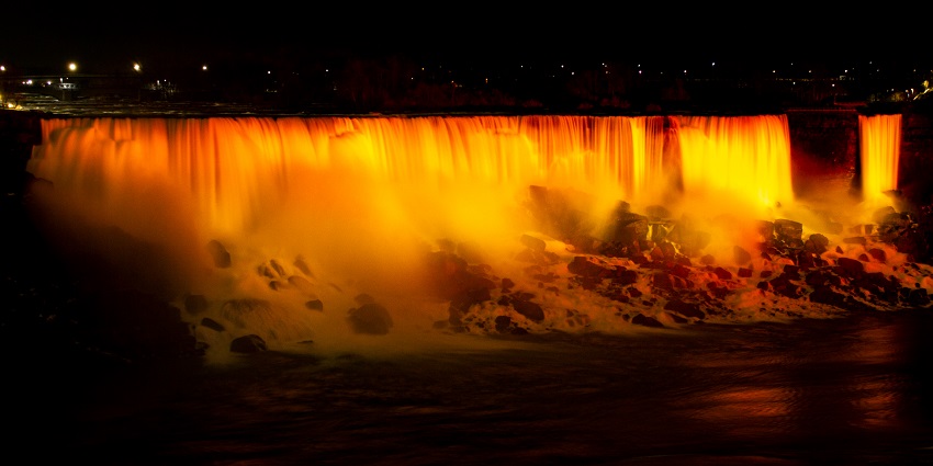 View of Niagara Falls from the American side, with cascading water and greenery.