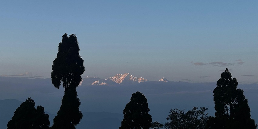 A scenic view of the snowy peaks of Kanchenjunga from the top of a hill in Darjeeling.