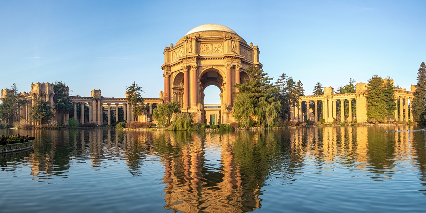 A distant view of the Palace of Fine Arts whose reflection can be seen in the water.