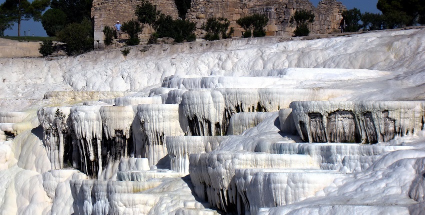 Natural thermal springs forming white travertine terraces and scenic landscapes.