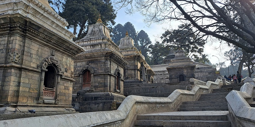 A monastery perched on a cliff surrounded by mountains and green nature on a sunny day.
