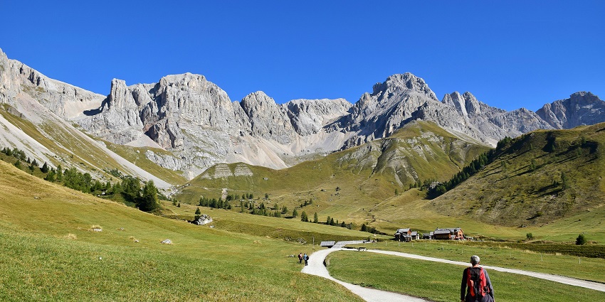 Image of a person hiking with dog on footpath in dolomites during day time