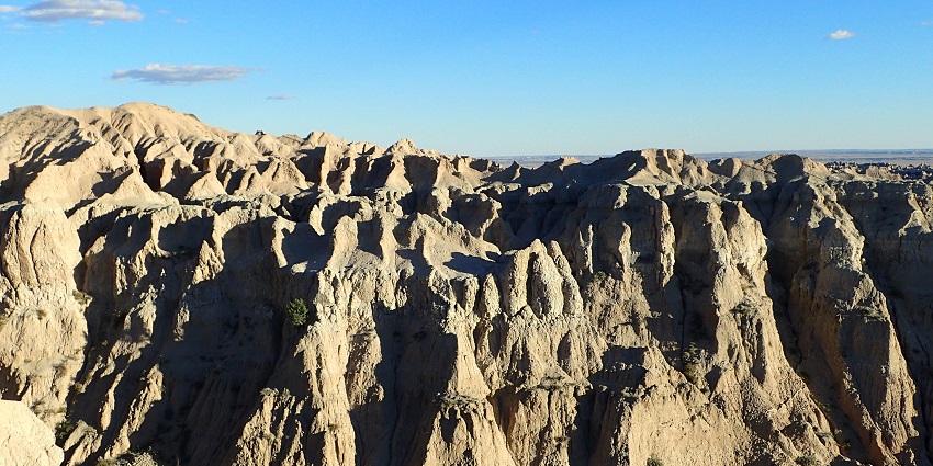 A view of layered rock formations and deep crevices showing badland terrain.
