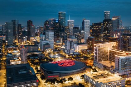 Downtown Houston at night with well-lit skyscrapers and a Toyota Center in the middle