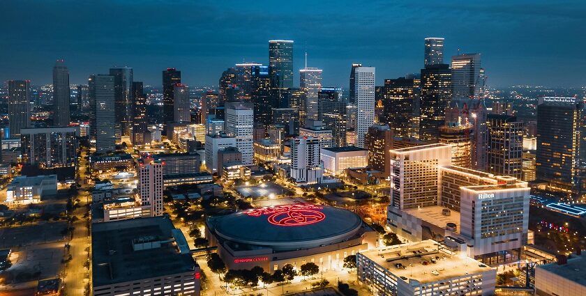 Downtown Houston at night with well-lit skyscrapers and a Toyota Center in the middle