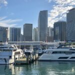 View of the lower Miami skyline with tall buildings and yachts anchored on Bayfront Park.