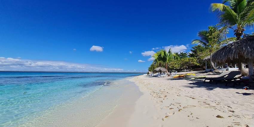 A beach during the daytime with clear turquoise waters gently flowing at a sandy shore.