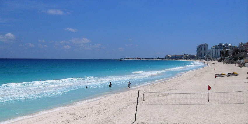 A panoramic view of Playa Delfines in Cancún, featuring a sandy beach with a few beachgoers