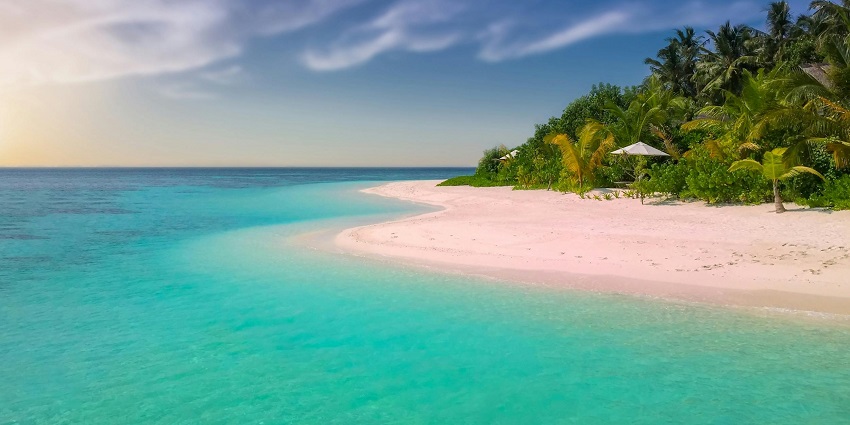 An aerial view of a lush island near Cancun's beaches featuring clear waters and greenery