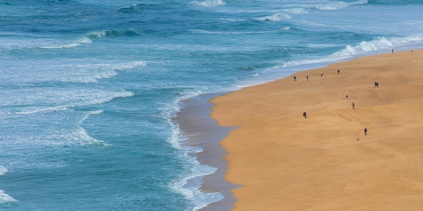 An image of the bustling Cancun beach with people walking on white sand near the quintana roo region