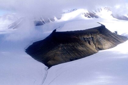 A rugged Arctic landscape with rocky terrain, scattered greenery, and a river in Nunavut.