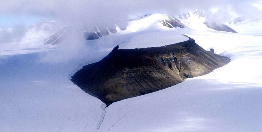 A rugged Arctic landscape with rocky terrain, scattered greenery, and a river in Nunavut.