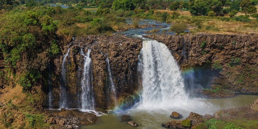 A picture of Rainbow Waterfalls in Lava, with sunlight creating a rainbow effect in the mist