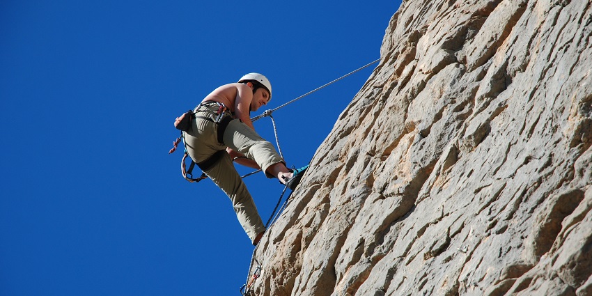 A picture of adventure enthusiasts rappelling down steep rock faces during their trek.