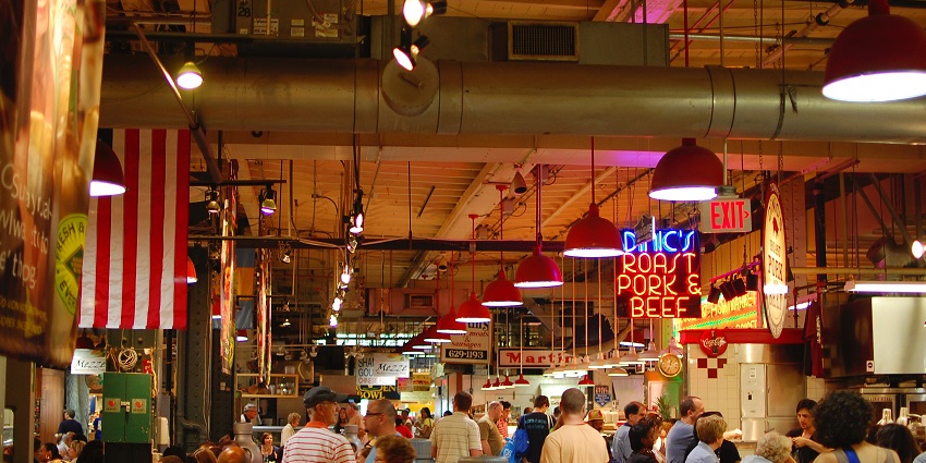 Reading terminal market complex filled with people and lamps hanging from the ceiling.