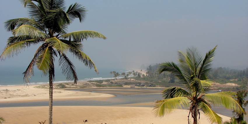 A serene view of Redi Beach with golden sands and gentle waves, under a clear sky