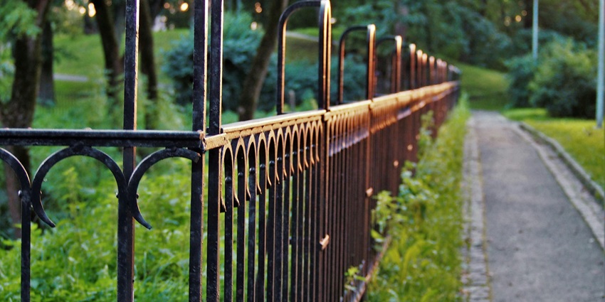 Visit this park with black metal fence with decorative spikes and curves, casting shadows on pavement, one of the best things to do in Park Street Kolkata.