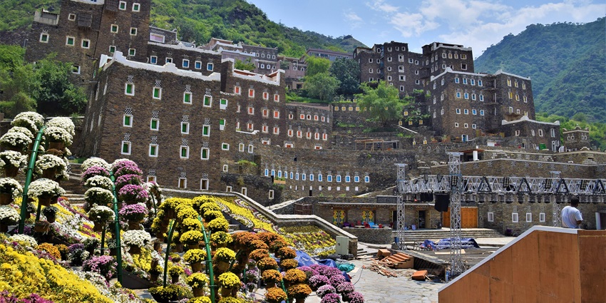 Colorful stone houses in Rijal Almaa village set against a backdrop of green hills.