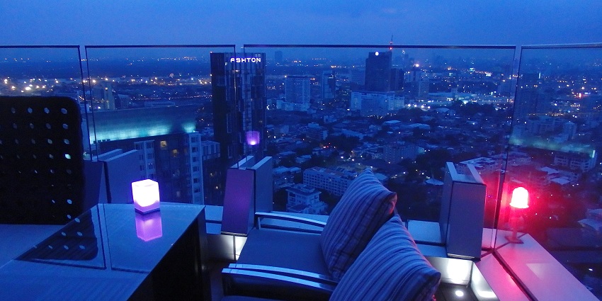 Rooftop bar with tables, a light on the table and tall buildings showcasing Sofia nightlife.