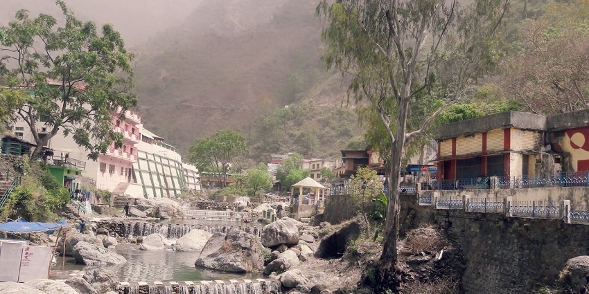 Serene waterfall and sulfur springs surrounded by lush hills.