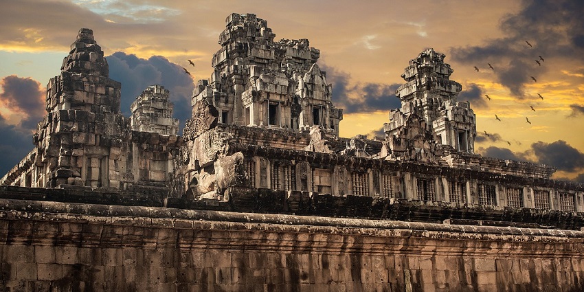 An image of a temple with ornate architecture and golden details under a blue sky with clouds.