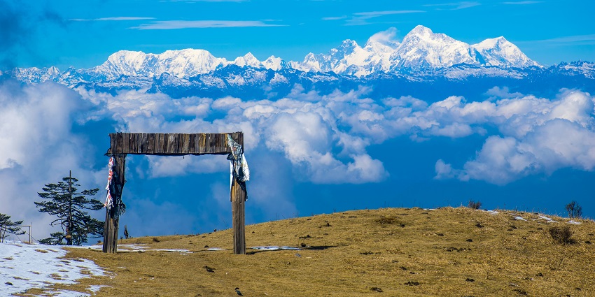A serene view of Sandakphu featuring snow-clad mountains and a blanket of clouds