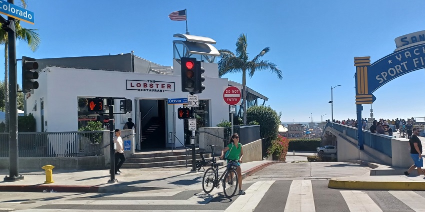Zebra crossing in front of a Lobster Restaurant and the Santa Monica Pier on a clear day
