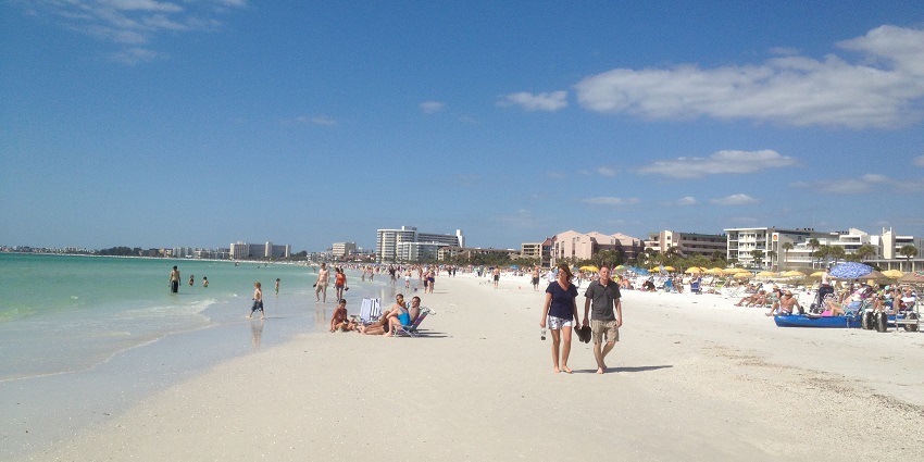 An image of soft white sands and gentle waves on Siesta Key Beach, Florida, under a bright sky