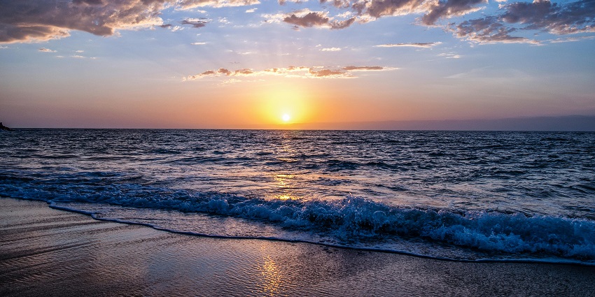 Long, sandy beach with calm waves and a scenic backdrop