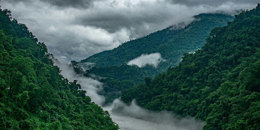 An awe-inspiring view of Siliguri featuring green-clad peaks and a gushing river.