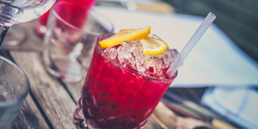 A picture of a refreshing cocktail with ice and a slice of lime, served in a glass.