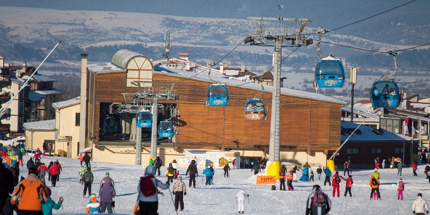 Ski lift in Bansko with people riding, ski lift pillars and people inside the trollies