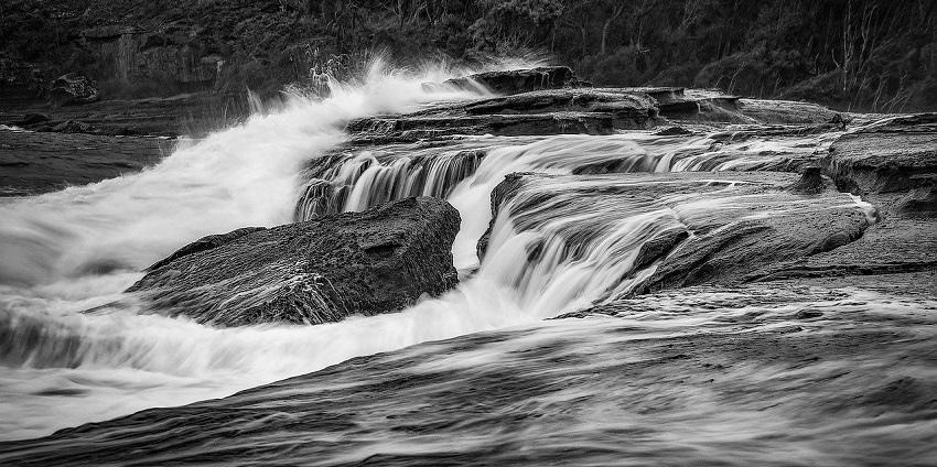 A stream of water flowing rapidly over rocks, one of the best places to visit near the Wood Buffalo National Park.