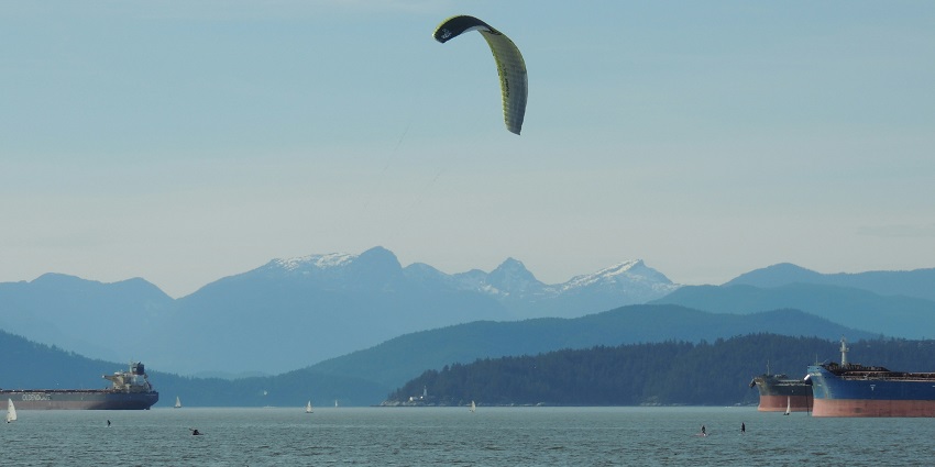 Waves are crashing on a long stretch of Spanish Banks where a few people are roaming.