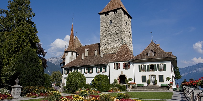 Historic castle overlooking Lake Thun with captivating gardens and views.