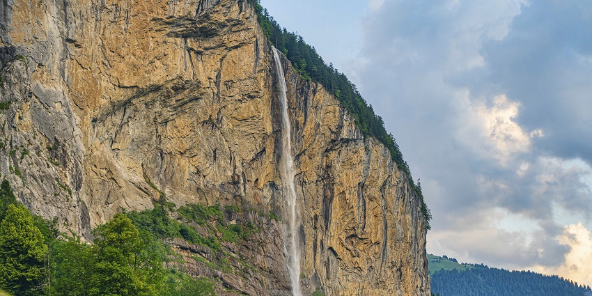 View of Majestic waterfall cascading down a cliff in Lauterbrunnen under clear blue sky