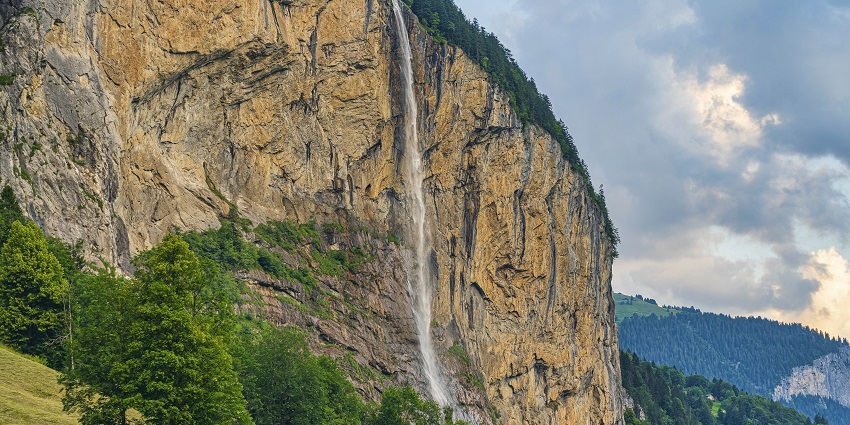 Switzerland waterfalls plunging from cliffs, framed by alpine scenery.